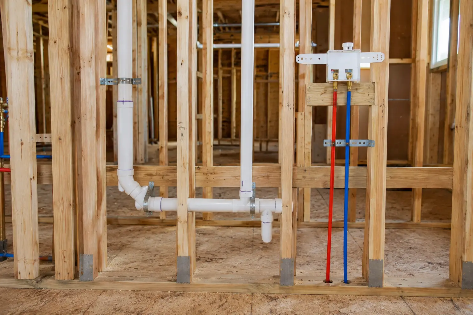 Licensed plumber installing rough-in water and drain piping during new construction.